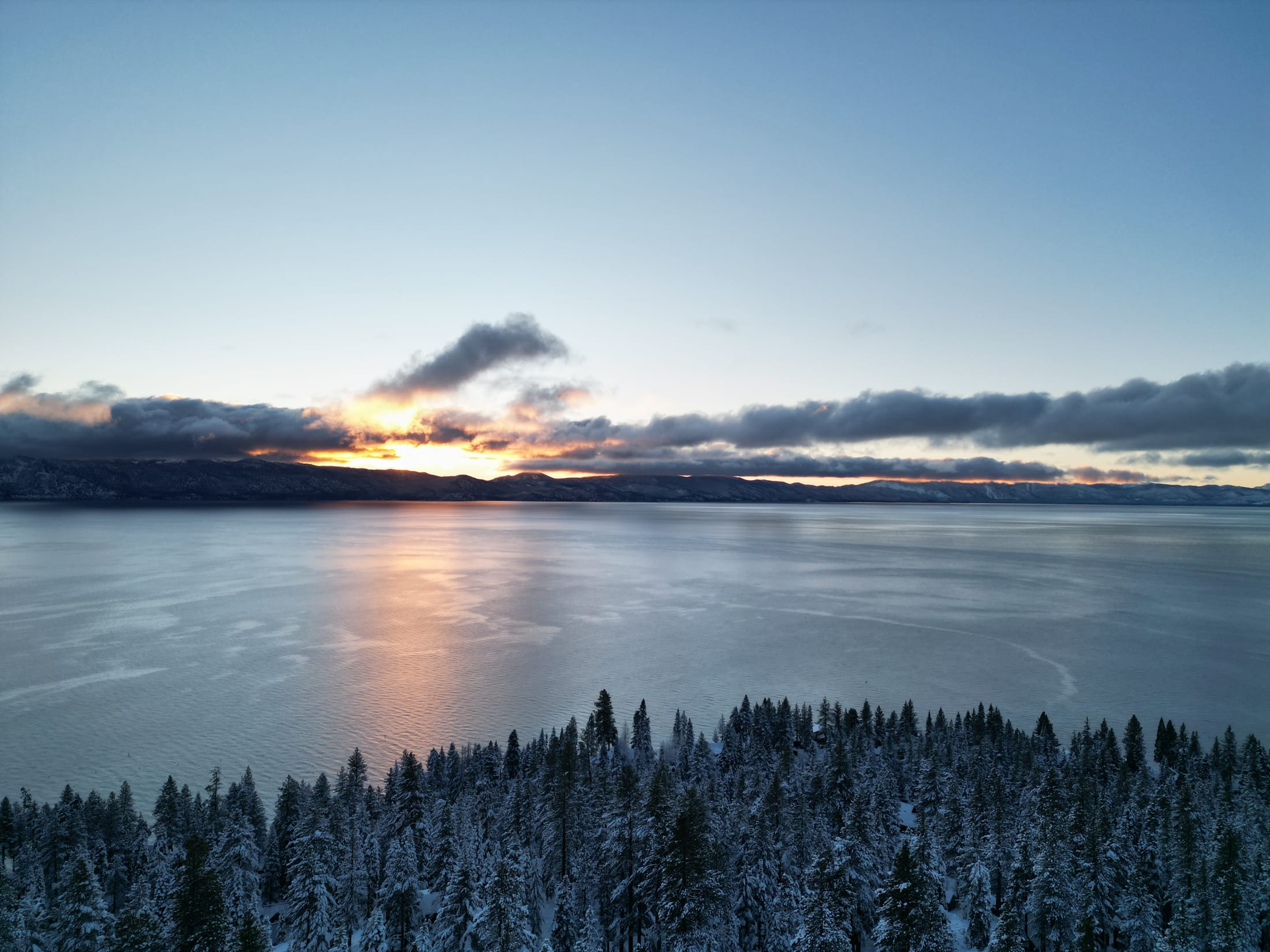 Lake Tahoe shoreline at first light with pines and snow-capped peaks